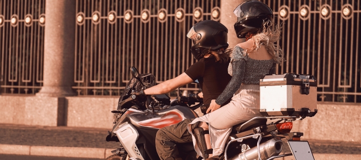 Two girls ride a motorcycle in the evening city.