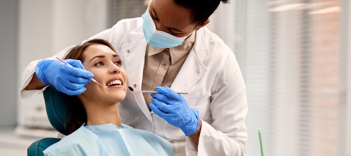 African American dentist examines a patient’s teeth.